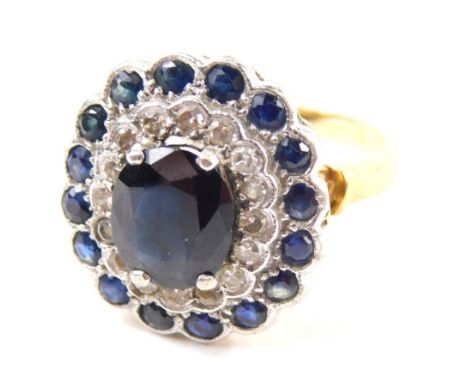 An 18ct diamond and sapphire dress ring, with a stepped floral setting on pierced shank, claw set with a central oval stone, 