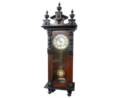 An early 20thC walnut cased Vienna wall clock, with broken arch pediment, cream coloured enamel dial with Roman numerals, etc