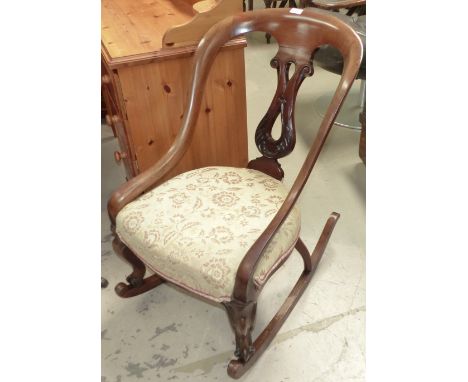 A Victorian mahogany spoon back rocking armchair with carved splat and cabriole legs