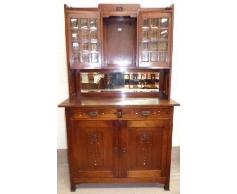 An Edwardian Arts & Crafts designer stained walnut mirror back side cabinet with carved flower head motifs, and inlaid pewter