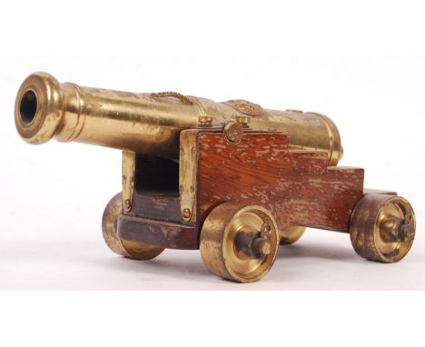 A reproduction scale desktop black powder naval cannon having a fruit wood base with brass wheels and brass barrel with The R