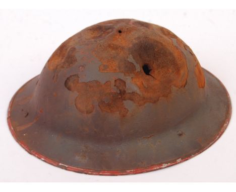 An original WWII Second World War British Army steel Brodie uniform helmet. Battle damaged, with a sniper bullet hole to top.