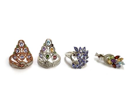 Three silver gem set rings and a brooch in the form of peacocks, set with a variety of gems including tanzanite, topaz, garne