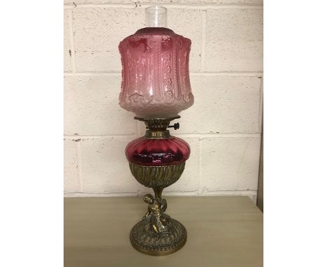 Antique Victorian cranberry glass oil lamp with brass cherub base approximately 57cm high
