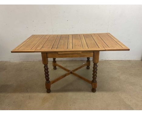 A light oak draw-leaf table raised on barley twist supports, width 91cm.