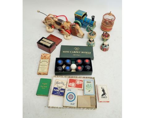 A box of games and toys including mini carpet bowls, advertising playing cards, mechanical bird in cage etc. 