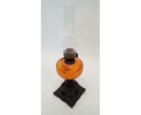 A Victorian cast iron oil lamp with orange glass reservoir 