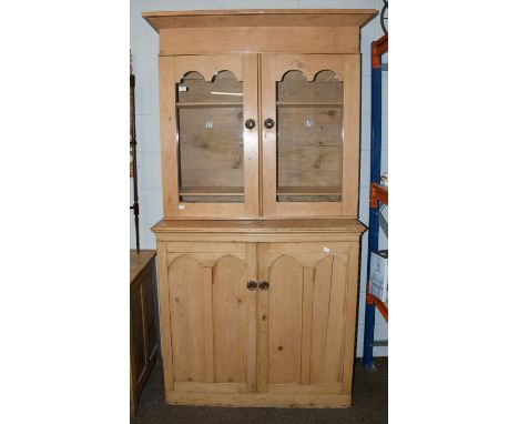 A Victorian Pine Bookcase, with arch top doors and glass handles, with glazed top section and cupboard below, 107cm by 49cm b