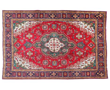 Tabriz CarpetNorth West Iran, circa 1960The raspberry field of stylised flowerheads and palmettes centred by a forest green a
