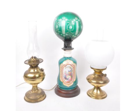 A collection of three late 19th century oil lamps, one converted to electric. Featuring two brass bodies and one ceramic, wit