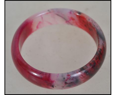 A Chinese Jade Bangle Bracelet, rose coloured stone carved in round tubular form