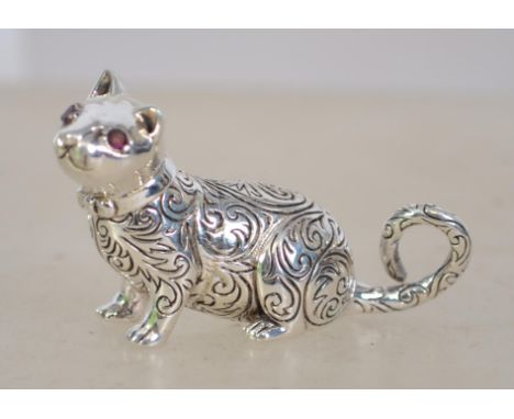 A cast silver figure of a cat with ruby eyes. Silver marks to base. Weighs 19.7 grams measures 3cms high.