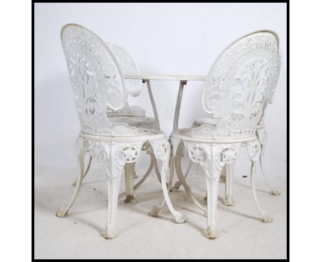 An antique style cast metal garden furniture patio set in the coalbrookdale style having table and 4 chairs painted white. Me