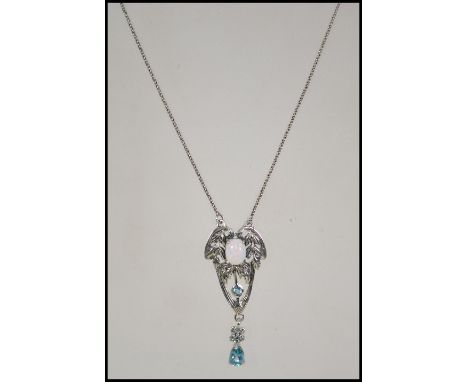 A silver Art Nouveau style pendant necklace set inset with a central opal and blue topaz drop