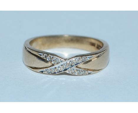 A hallmarked 9ct gold and diamond band ring with illusion set diamonds in a kiss motif. Hallmarked Birmingham. Weight 2.9g. S