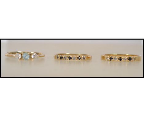 A pair of 18ct gold plated sapphire and rhinestone rings along with another aquamarine and clear stone ring. The sapphire rin