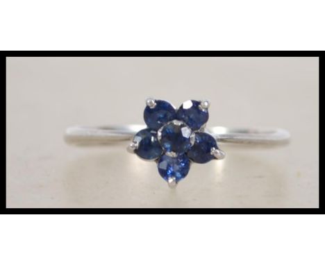 A 14ct white gold daisy ring set with blue stones in a flower head setting. Marked 14k. Total weight 1.9g. Size .