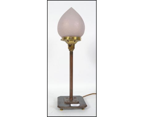 A 20th century Art Deco copper lamp on a two tier terraced base having a frosted pink glass bud shade.