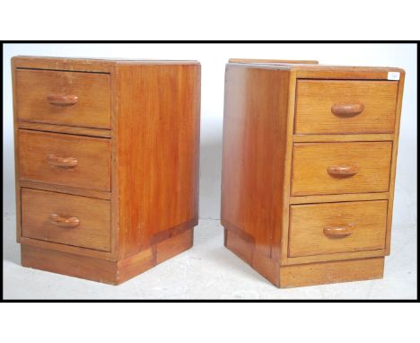 A pair of vintage mid century oak &nbsp;G plan bedside tables, each with a run of three straight drawers raised on a plinth b