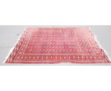 A large carpet rug having a russet red ground with a tribal design. Measures 220cms x 300cms