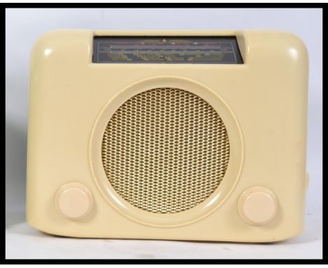 A vintage mid 20th century bakelite bush type DAC 90 valve radio in a cream bakelite. Dials and knobs to the top and a circul