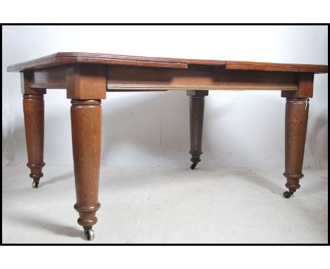 A large Victorian twin leaf wind out dining table being raised on turned tapering legs with ceramic castors. Complete with tw