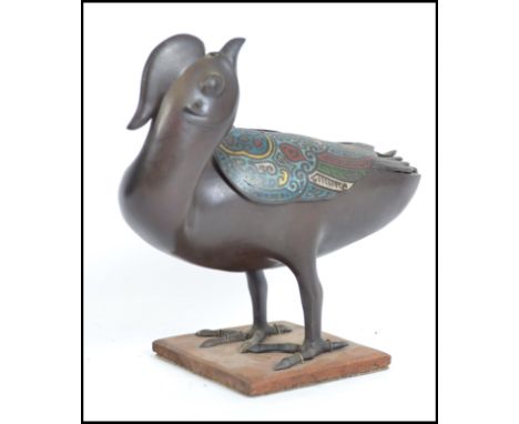 A Chinese bronze and enamel decorated incense burner in the form of a duck having pierced swivel top and raised on wooden pli