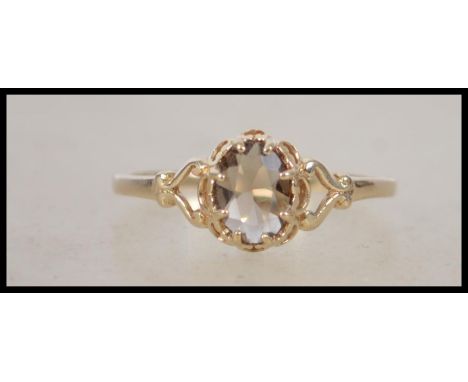 A 9ct gold hallmarked gold single stone ring. The ring set with lattice worked mount, single smokey quartz stone to centre. H