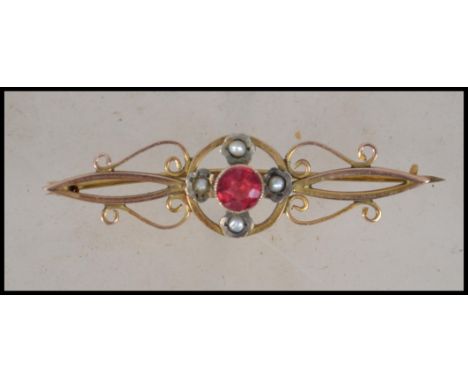 A vintage early 20th century 9ct gold ladies bar brooch with inset red stone to centre being round cut with seed pearls. Tota