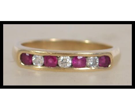 A 9ct gold hallmarked 7 stone ring set with 3 round brilliant cut diamonds and 4 round cut rubies in a channel setting. &nbsp