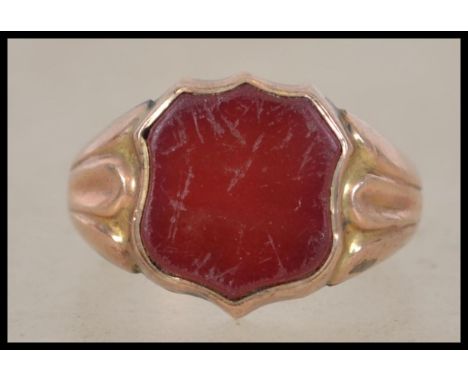 A hallmarked 9ct gold signet ring having an armorial shield shaped central red agate stone panel. Weighs 3.25 grams size N.