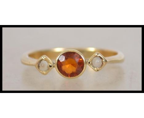 An 18ct gold ring set with an orange stone in a rub over setting flanked by two mother of pearl. Marked 18ct tests 18ct gold.