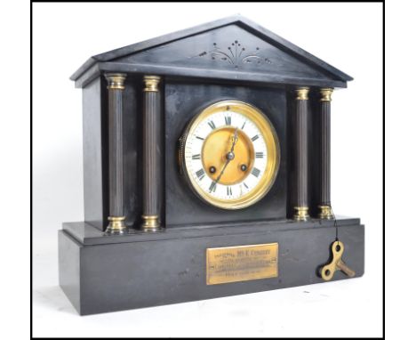 A Victorian black slate mantle clock, with columns to front, faceted hands, and original key and pendulum. Plaque to front wi