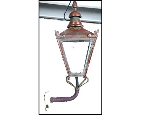 An early 20th century copper wall mounted street lantern. Of square tapering form complete with wall bracket and copper finia