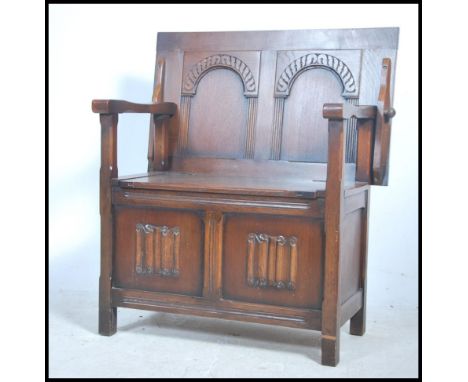 A good mid century solid oak monks bench table having a panel base with carved details having hinged lid with adjustable back