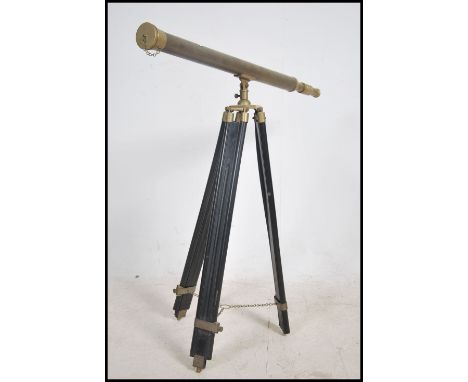 A 20th century brass two draw telescope raised on an ebonised adjustable folding tripod support. Measures 105cm high as pictu