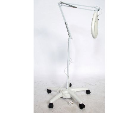 A 20th century Industrial medical floor standing anglepoise magnifying lamp raised on castor base with lamp atop