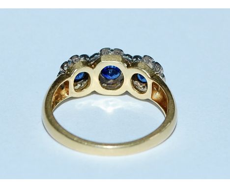 A hallmarked 18ct gold blue sapphire and diamond ring. The ring being set with three round cut sapphires surrounded by halos 