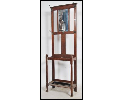 A 1930's oak hallstand / umbrella stand raised on squared legs with stick stand base having mirror atop flanked by coat hooks
