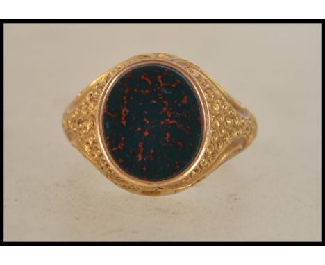 A 15ct gold marked signet ring having a central bloodstone agate panel with stylised shoulders. Weighs 3.25 grams size R.