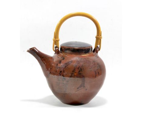 DAVID LEACH (1911-2005) for Lowerdown Pottery; a stoneware teapot with cane handle covered in khaki glaze with faint traces o
