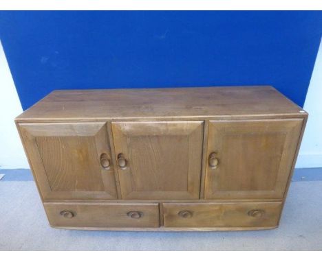 A light elm Ercol sideboard of three cupboards above two drawers, raised on castors. 