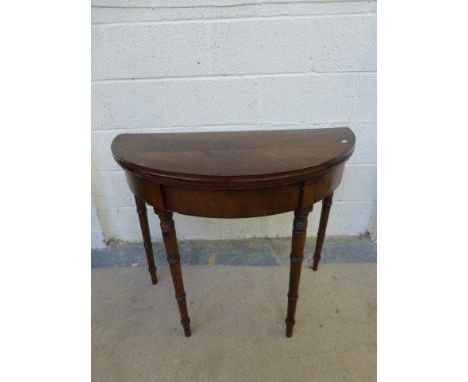 A Georgian mahogany demi lune fold over card table with green baize interior raised on four turned tapering supports. 