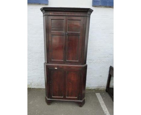 An 18th Century oak two piece floor standing corner cupboard of good colour, the upper section with two doors, above a single