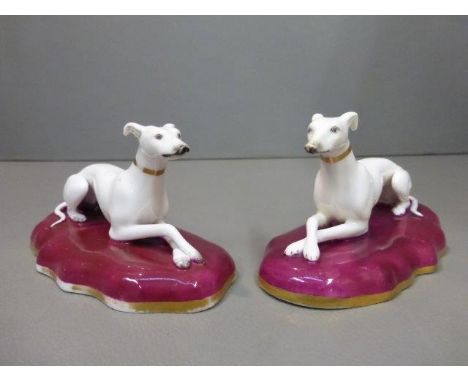 A pair of 19th Century ceramic recumbent greyhounds on shaped bases. 