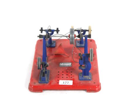 A Mamod steam engine accessories plate with pulley and various accessories including a hammer, grinder, polisher and small pr