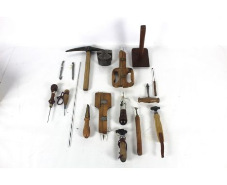 A box of tools including two lever pincers, a long metal needle, a leather stitching awe, a small saw etc.