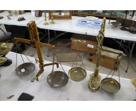 A set of brass balance scales with a set of brass weights and a set metal balance scales with brass hanging trays 