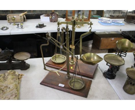 Two sets of brass balance scales set to wooden plinths , one missing a tray