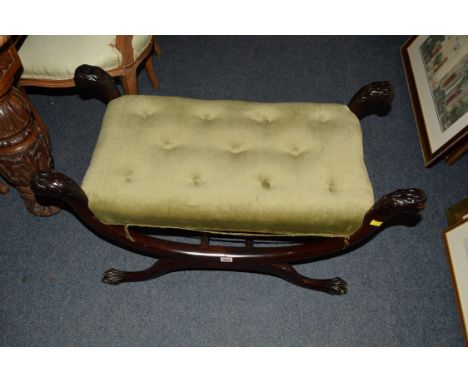 An antique mahogany and button upholstered X frame stool, with lion's head terminals and claw fee, 84cm wide. 